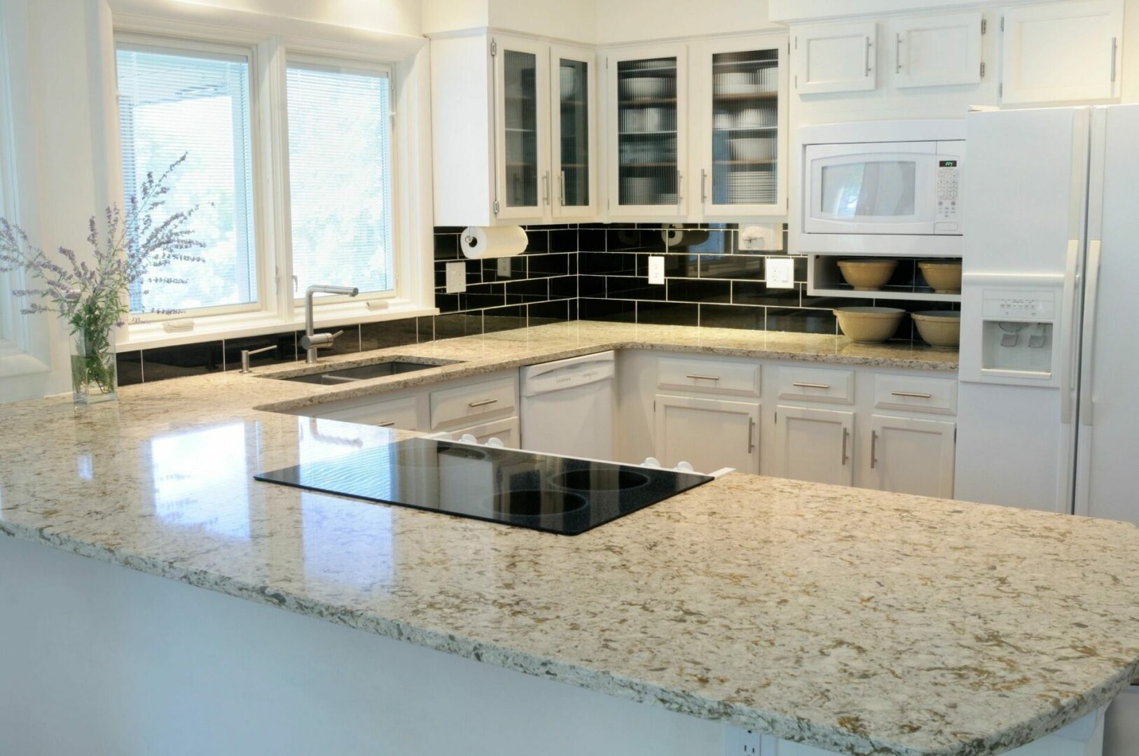 A kitchen with white cabinets and black counter tops.